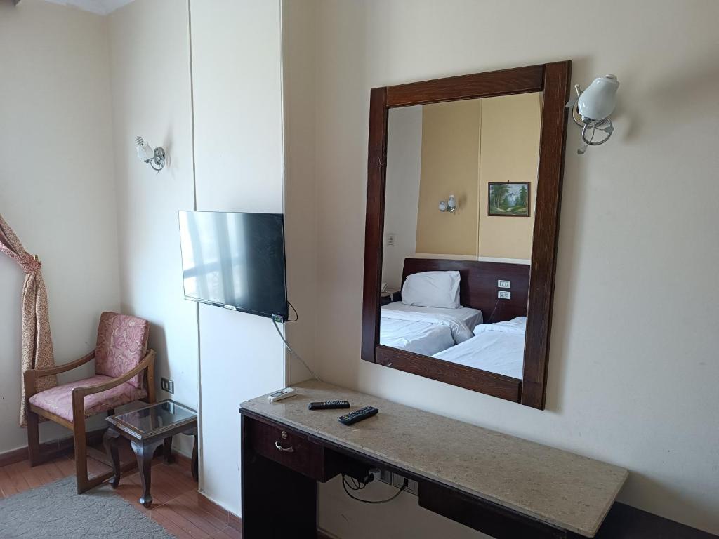 a bedroom with a mirror and a bed and a chair at Susanna Hotel Luxor in Luxor
