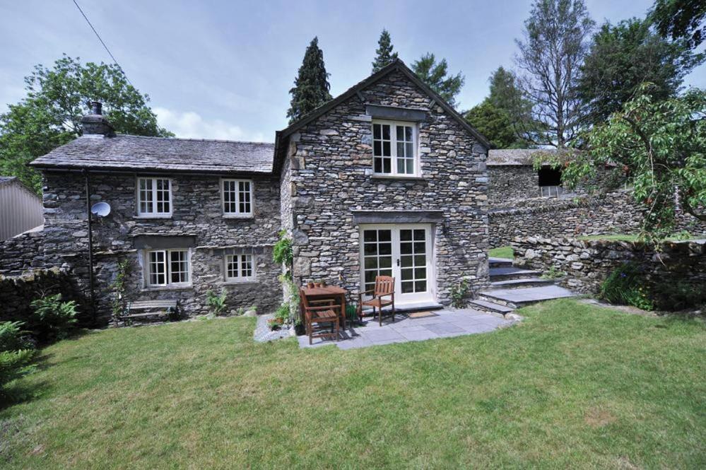 ein altes Steinhaus mit Rasen davor in der Unterkunft Stone Arthur Cottage in Grasmere