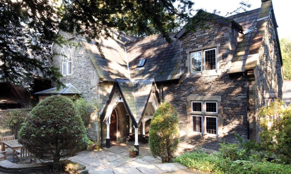 an old stone house with a bench in front of it at Priory Lodge in Windermere
