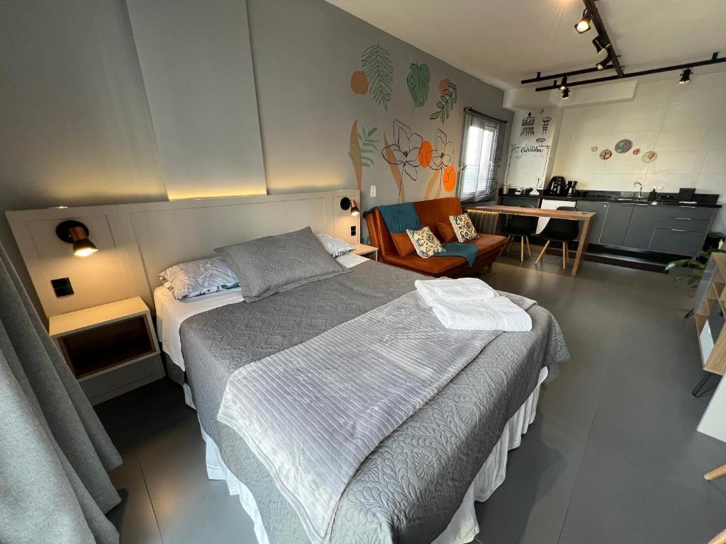 a bedroom with a large bed and a kitchen at Stúdio 11 11 Cristo Rei in Curitiba