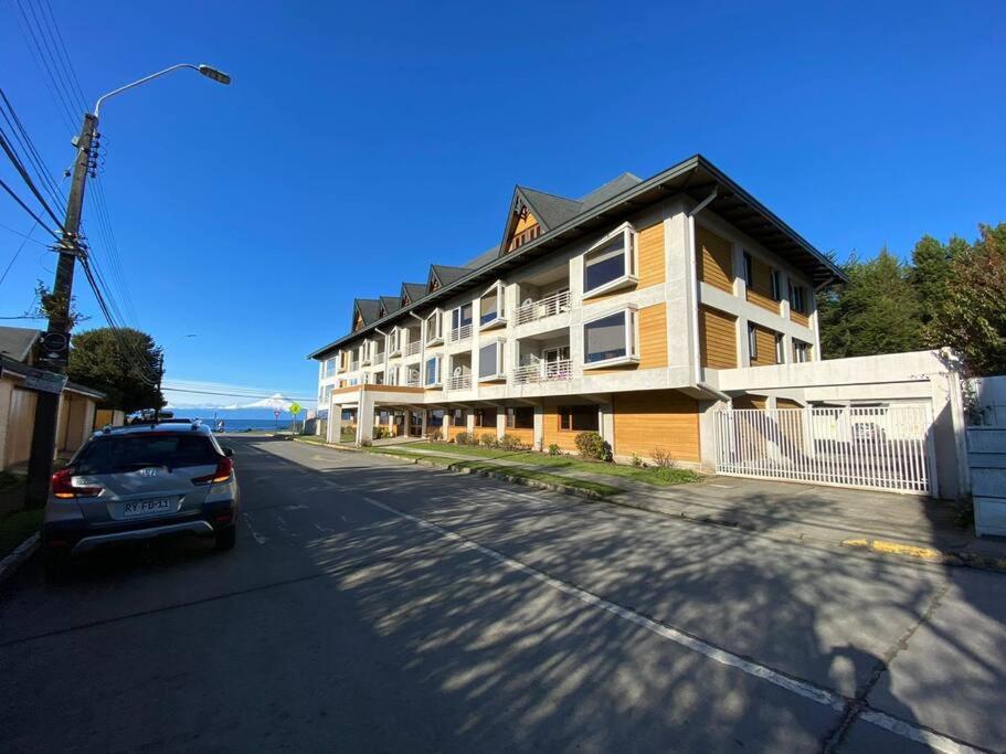 a car parked in front of a large building at Hermoso departamento en playa Frutillar Bajo in Frutillar