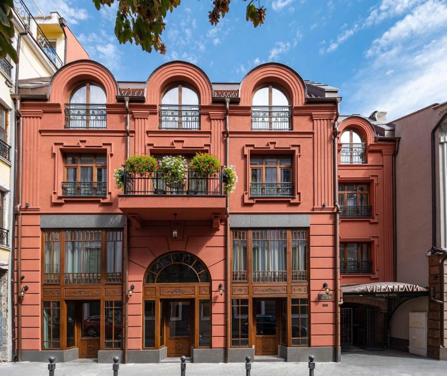 a red building with windows and potted plants at Villa Flavia Heritage Boutique Hotel in Plovdiv