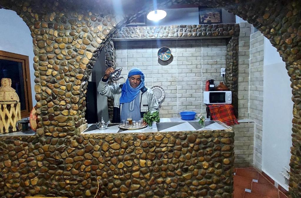 a woman standing in front of a mirror in a kitchen at Dar Agham Akbou in Timimoun