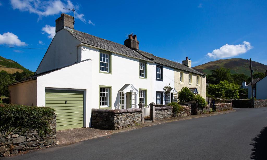 a white house with a green garage on a street at Kent Cottage in Cockermouth