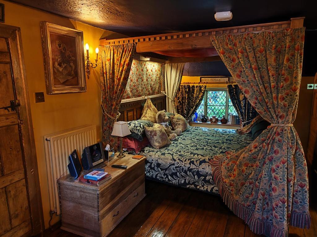1 dormitorio con cama, escritorio y ventana en Wizards Thatch Luxury Suites, en Alderley Edge