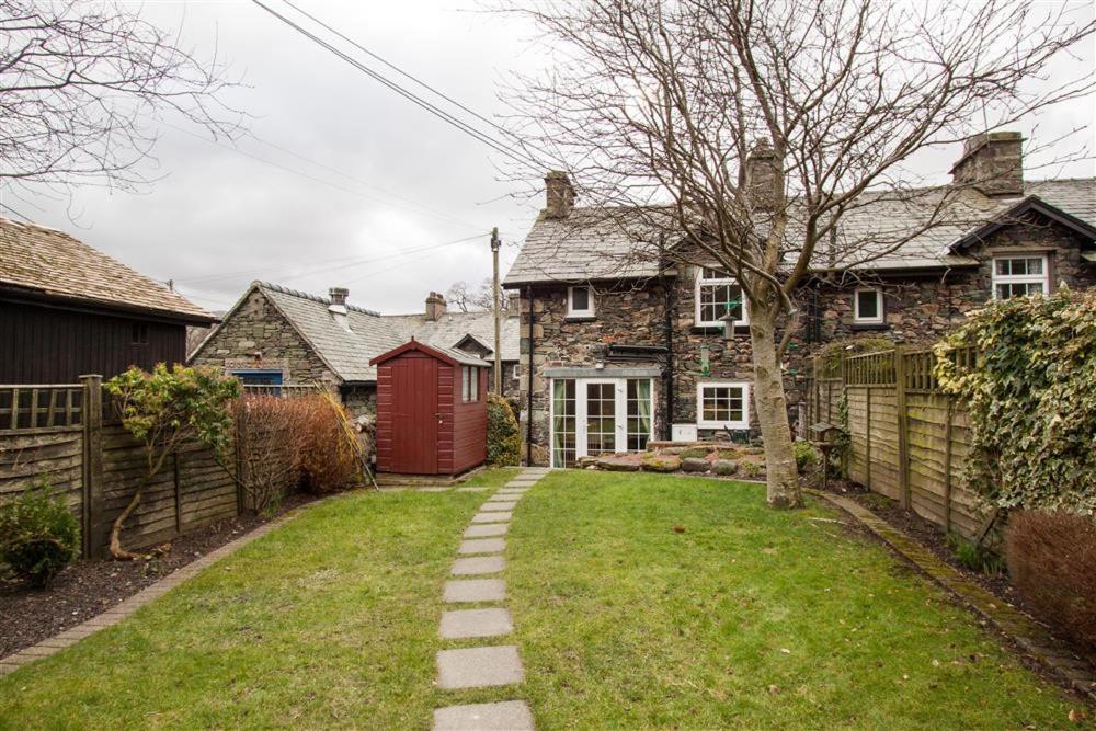un patio con una casa con una puerta roja en Bleaberry Cottage en Penrith