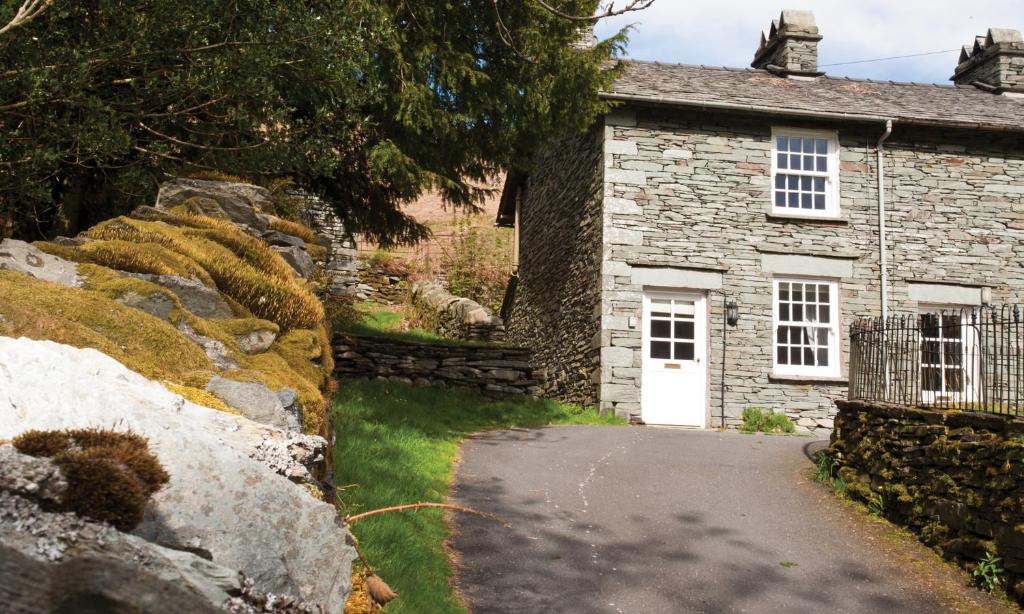 a stone cottage with a white door and a driveway at Beck Steps in Chapel Stile