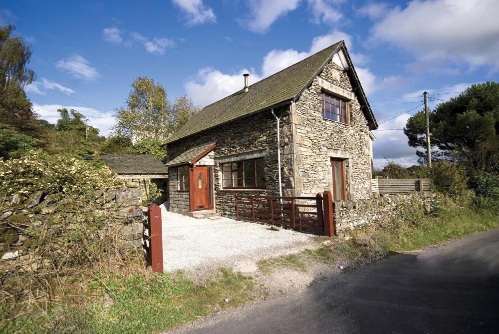 una pequeña casa de piedra con una puerta y una valla en The Old Chapel, en Windermere