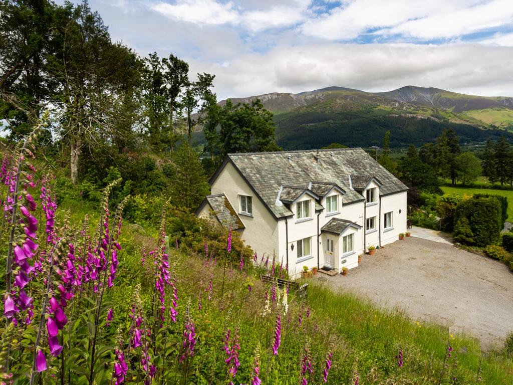 a white house on a hill with purple flowers at Kirkstones in Keswick