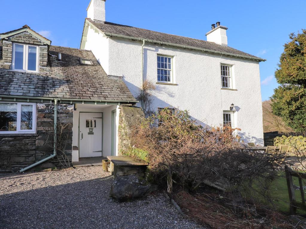 a white house with a bench in front of it at Robin Cottage in Troutbeck