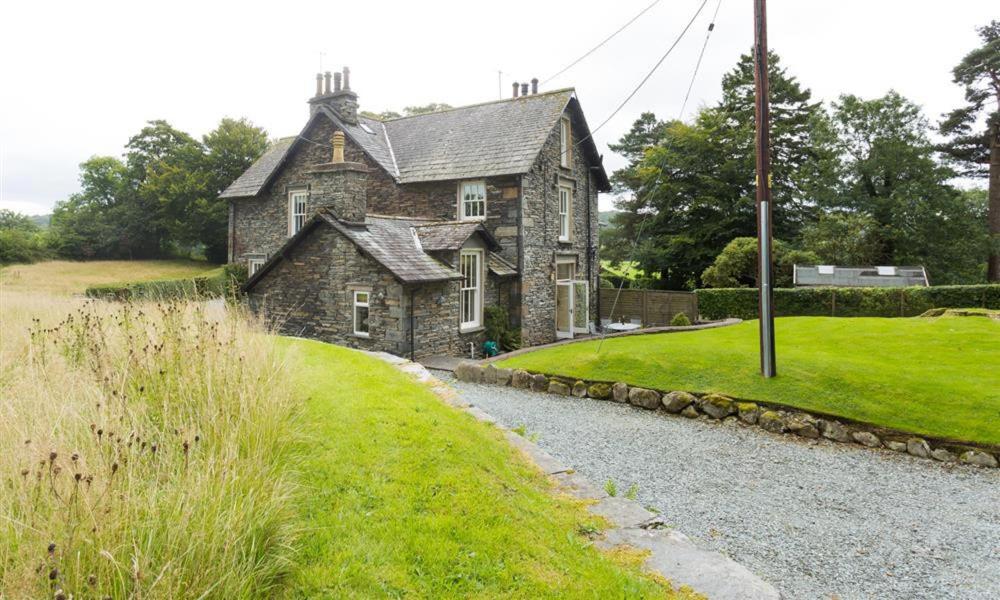 an old stone house sitting on a grassy hill at Hawkshead Hall in Hawkshead