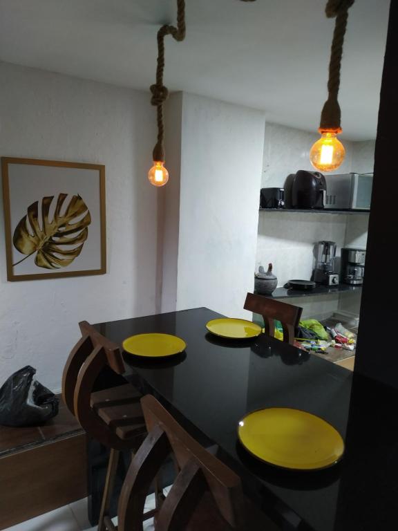 a kitchen with a black table with yellow chairs at No coração do Pelourinho, perto de tudo. in Salvador