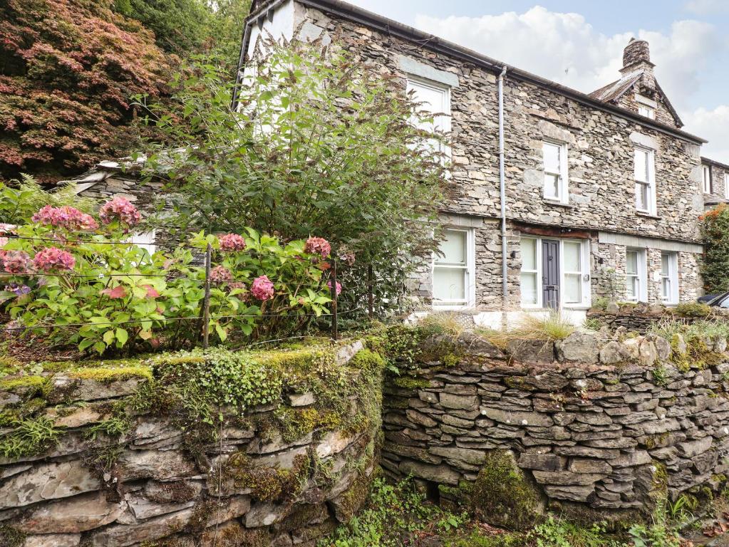 an old stone house with flowers on a stone wall at The Mews in Ambleside