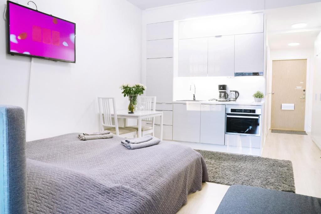 a white kitchen with a bed and a tv on a wall at Culture center of Oulu studio in Oulu