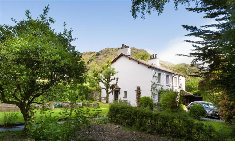 a white house with a hill in the background at Rose Cottage Coniston in Coniston