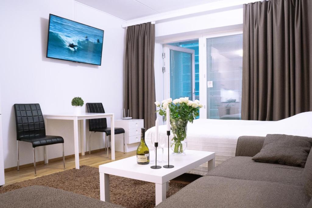 ein Wohnzimmer mit einem Sofa und einem Tisch mit Blumen in der Unterkunft City center 1R studio with perfect view, parking in Oulu