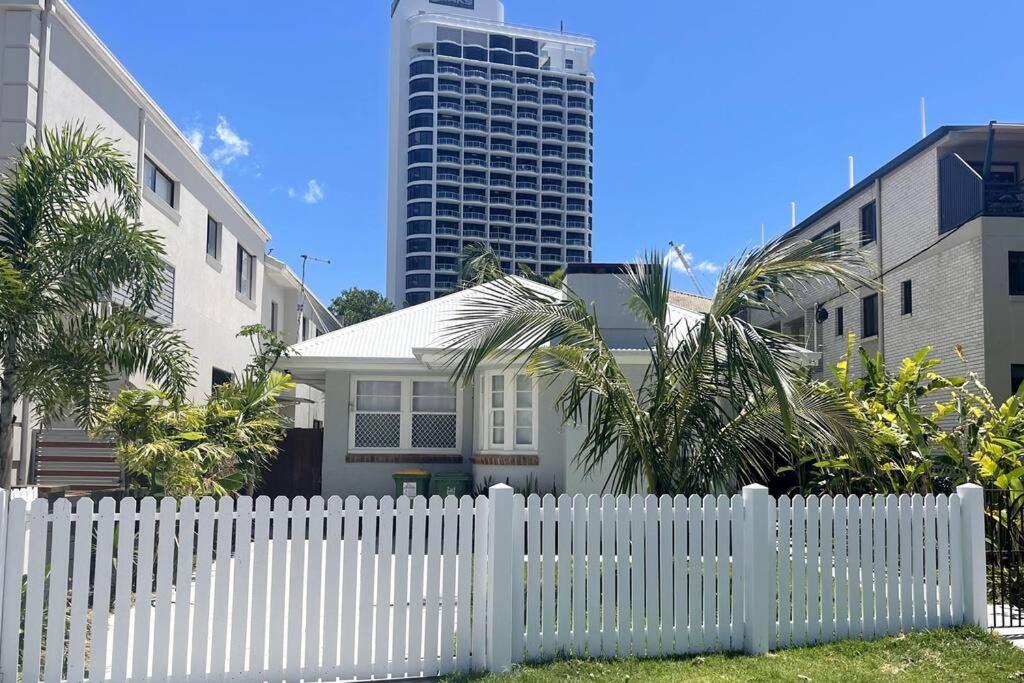 uma cerca branca em frente a uma casa com um edifício alto em Beach House 100ms to Beach Freshly Renovated All New Appliances em Gold Coast