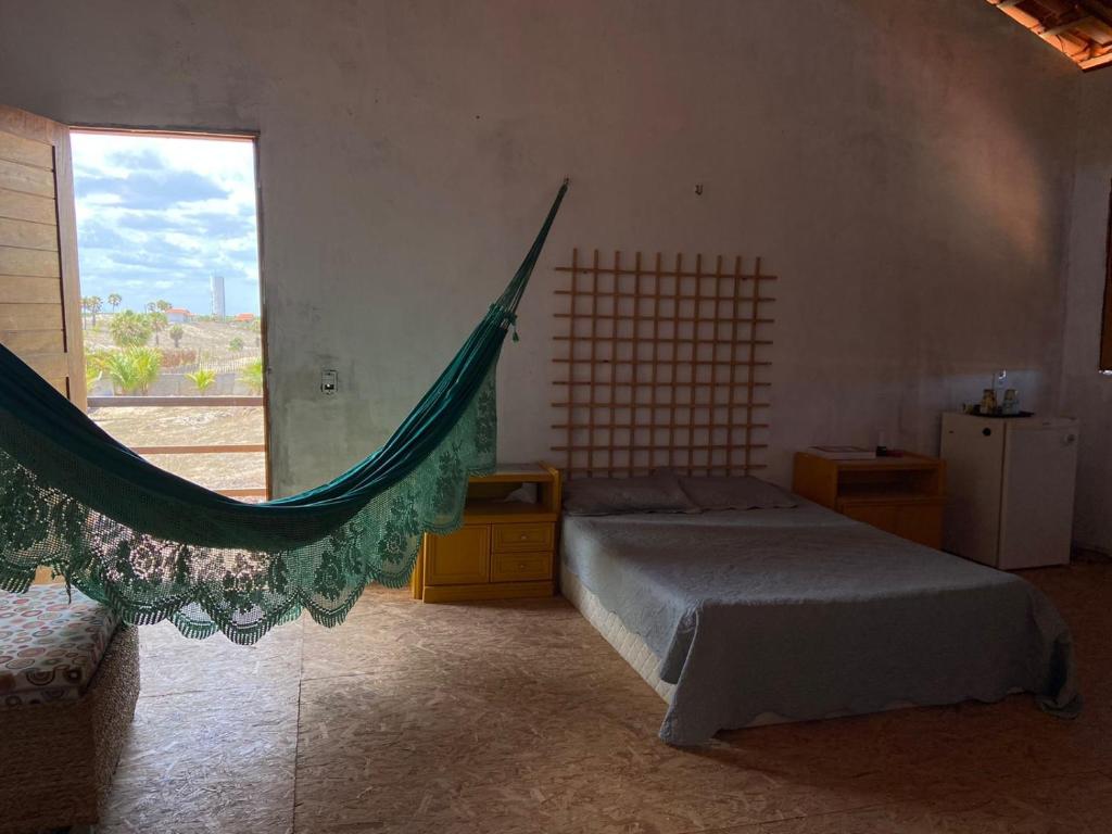 ein Schlafzimmer mit einer Hängematte in einem Zimmer mit Fenster in der Unterkunft Chalé na Praia de Macapá Piaui in Luis Correia