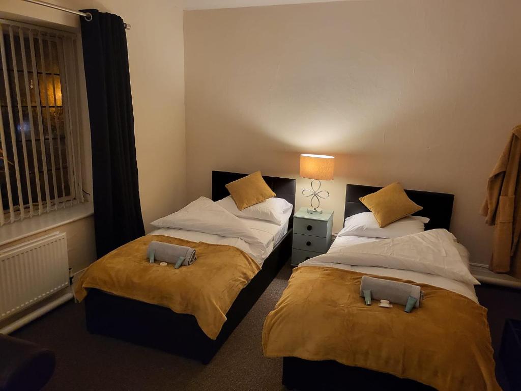 a bedroom with two beds and a lamp and a window at The Jubilee Inn - Bar & Kitchen in Litherland