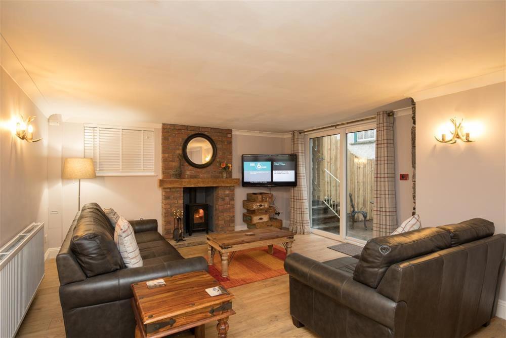 a living room with two leather couches and a fireplace at Chapel Hill Cottage in Ambleside