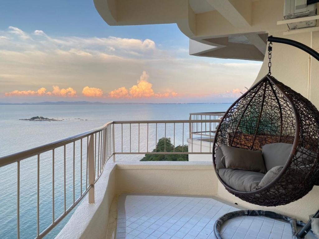 a hanging chair on a balcony overlooking the ocean at Rainbow paradise @ Tanjung Bungah in Tanjung Bungah