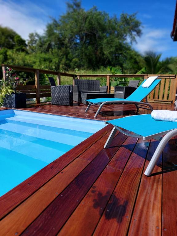 eine Terrasse mit einem Pool und Stühlen auf einer Holzterrasse in der Unterkunft Villa case Créole in Le Moule