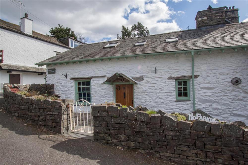 une maison blanche avec une clôture en pierre devant elle dans l'établissement Lowfold Cottage, à Ambleside