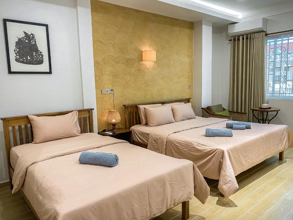 2 Betten in einem Hotelzimmer mit blauen Kissen darauf in der Unterkunft Muni Residence & Spa in Battambang