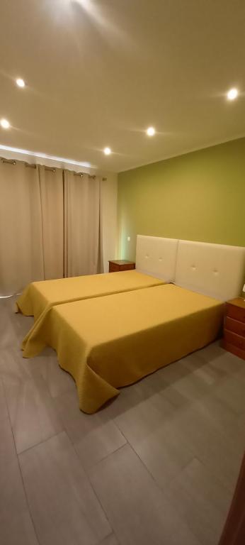um quarto com uma grande cama amarela num quarto em Rocha Apartment em Portimão