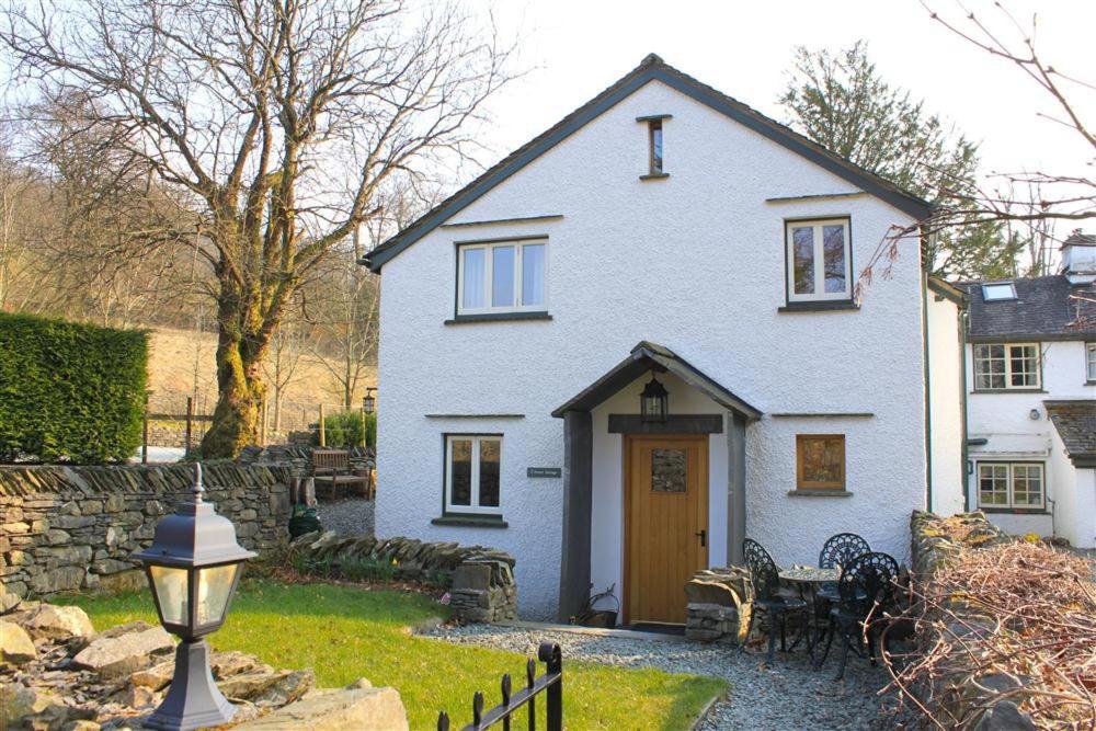 a white house with a wooden door in a yard at Forest Cottage in Coniston