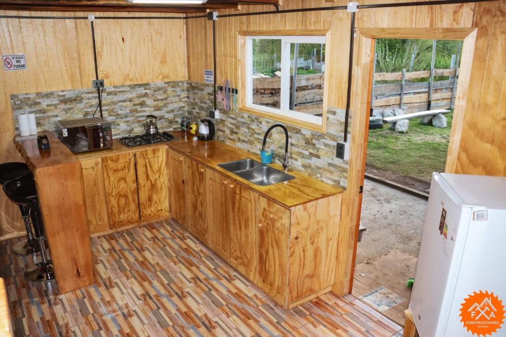 - une cuisine avec des placards en bois et un évier dans une cabine dans l'établissement Cabaña Río Noroeste, à Futaleufú