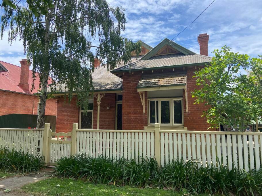 a red brick house with a white fence at Central CBD House in Wagga Wagga