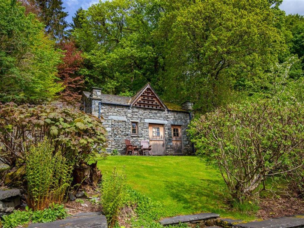 an old stone house in the middle of a yard at Dovecot Cottage in Ambleside