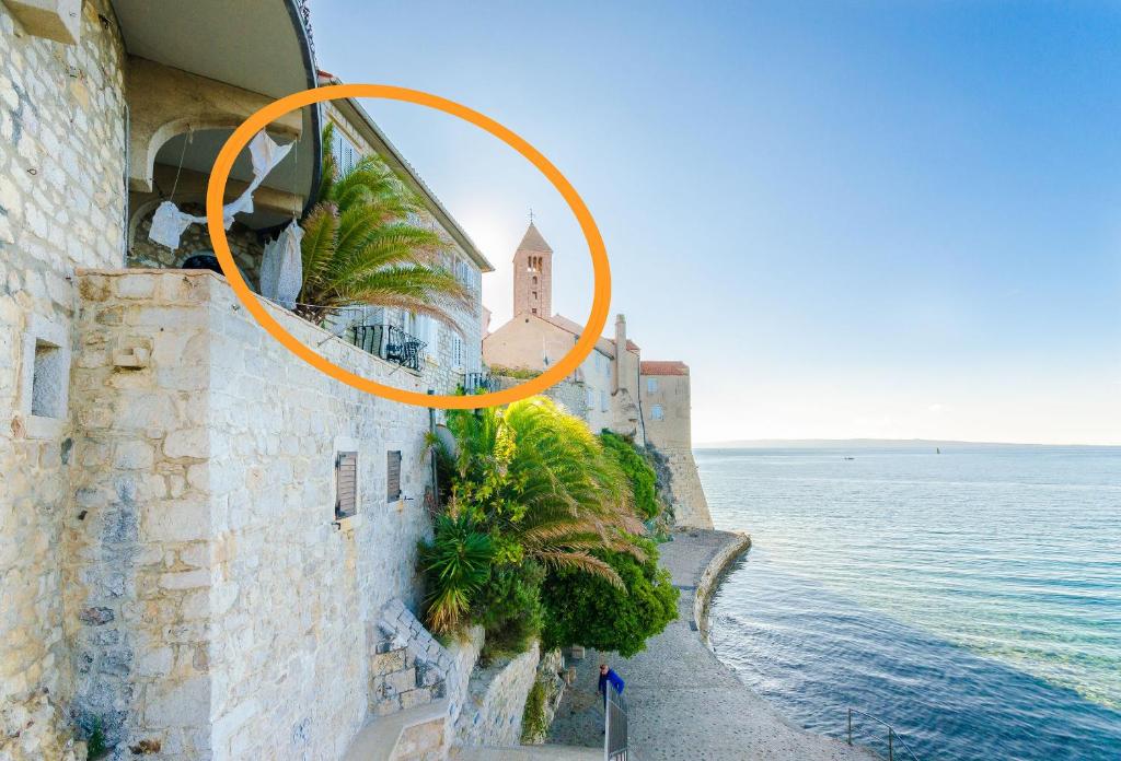 an orange circle on the side of a building next to the ocean at Rooms Sonja P in Rab