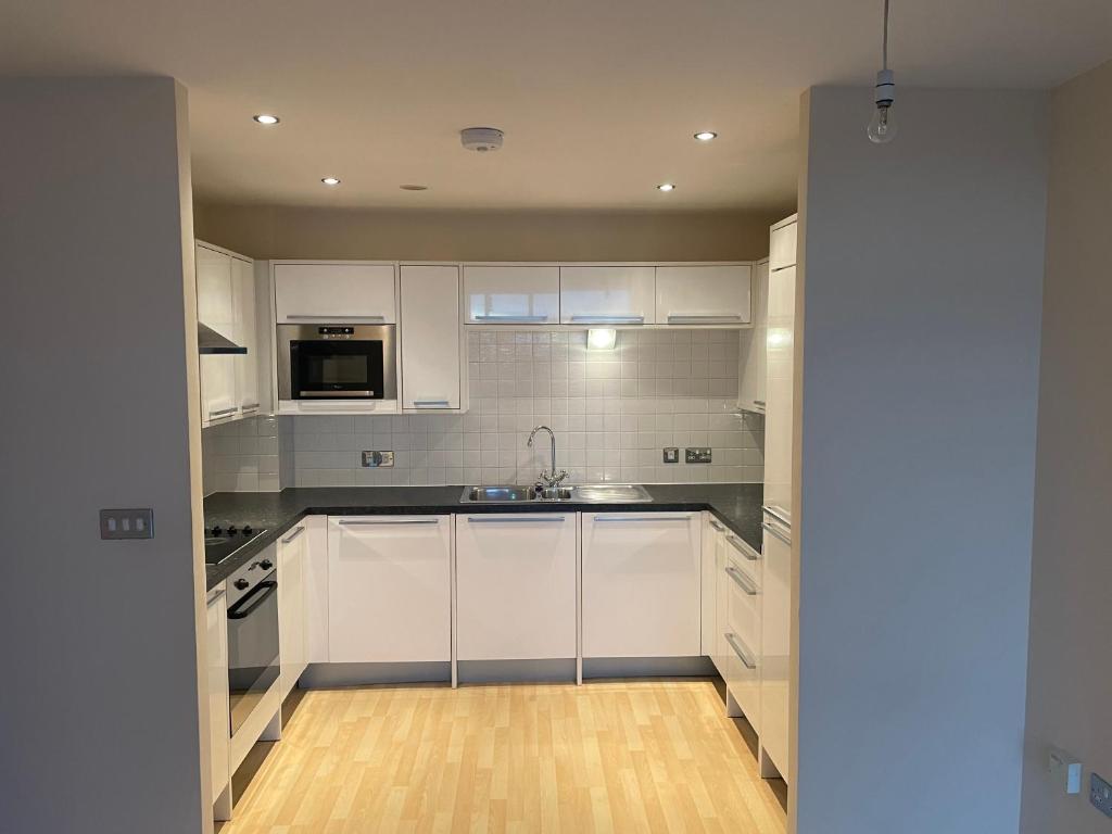a kitchen with white cabinets and a sink at High vibes home in Chelmsford