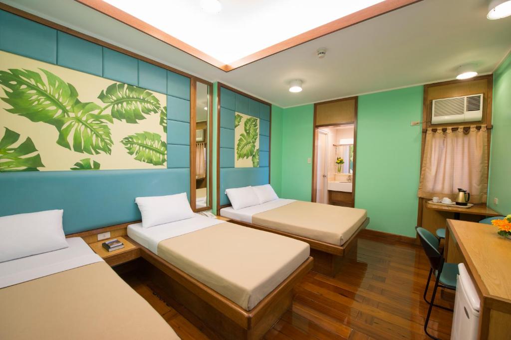 マニラにあるKabayan Hotel Pasayの緑の壁の部屋にベッドが2つある