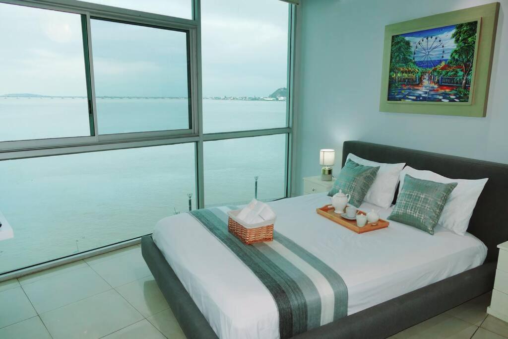 1 dormitorio con 1 cama grande y ventanas grandes en Departamento Familiar Riverfront, en Guayaquil