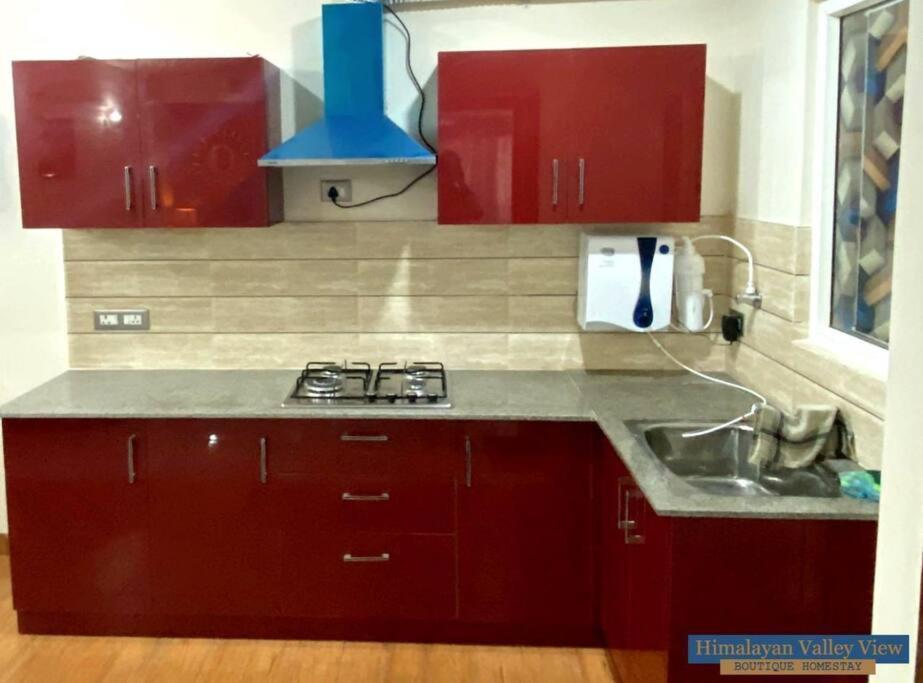 a kitchen with red cabinets and a sink at Himalayan Valley View - A boutique homestay in Dehradun