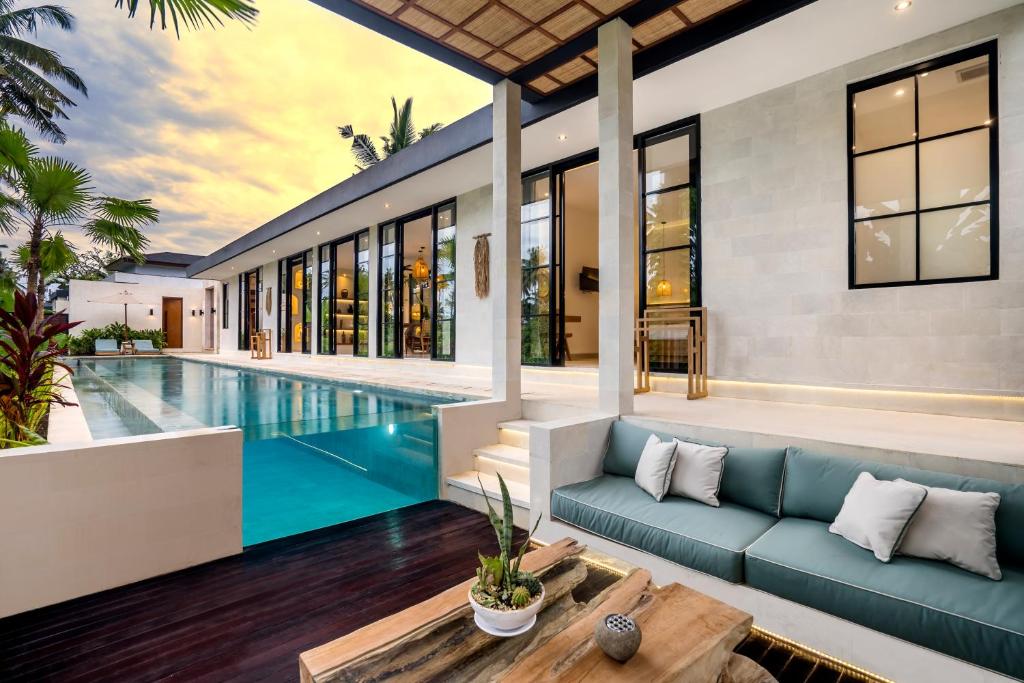 een woonkamer met een blauwe bank en een zwembad bij Villa Maria by BaliSuperHost in Ubud