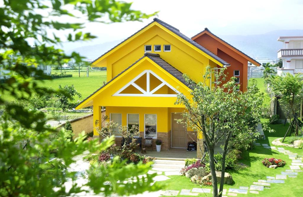 una casa amarilla con un patio verde en The Dew B&B, en Dongshan