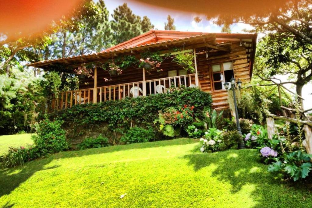 a log cabin with a lawn in front of a house at PROVENZA en Los Naranjos in Juayúa