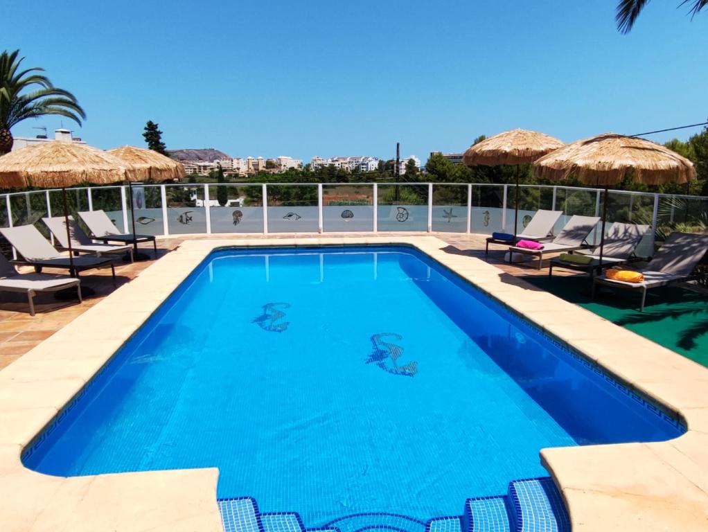a swimming pool with chairs and umbrellas on a building at Villa Gota de Mar in Jávea