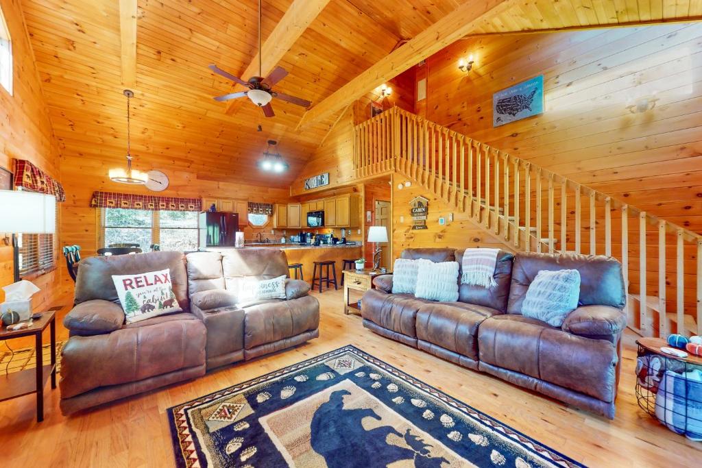 a living room with two leather couches and a staircase at Bear Essentials in Sevierville