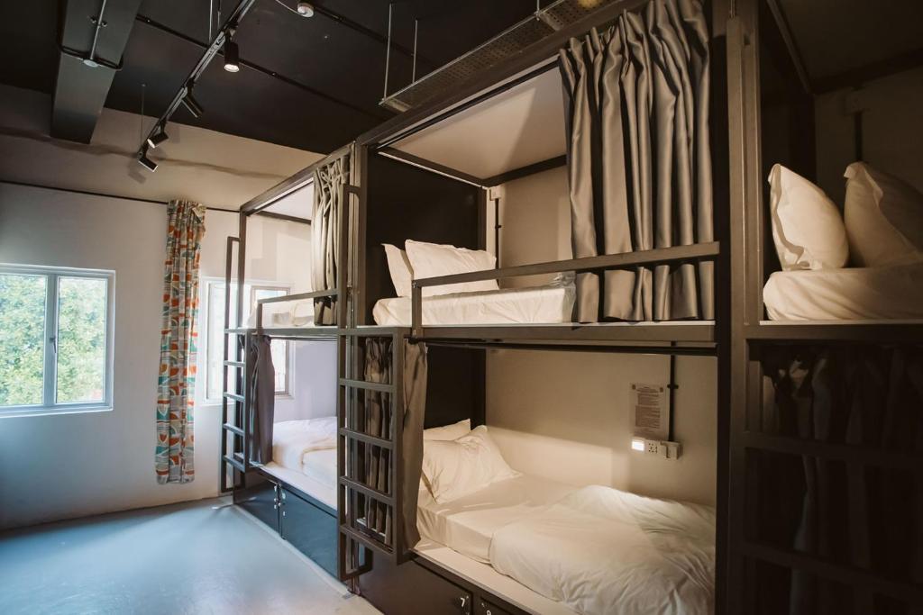 a room with three bunk beds with white sheets at 7 Wonders Hostel @ Boat Quay in Singapore
