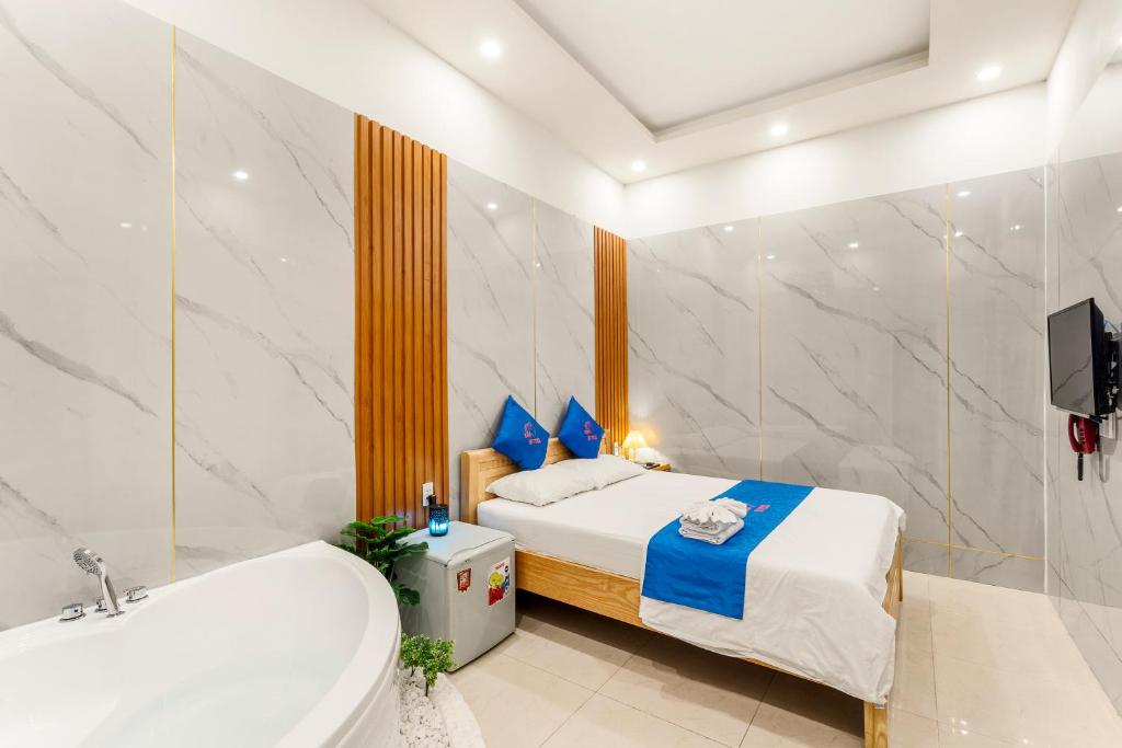 Schlafzimmer mit einem Bett, einer Badewanne und einer Badewanne in der Unterkunft KISS Hotel Tân Bình in Ho-Chi-Minh-Stadt