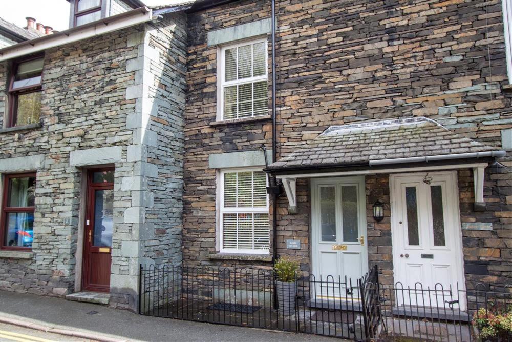 a brick house with a white door and windows at Acorn Cottage in Ambleside