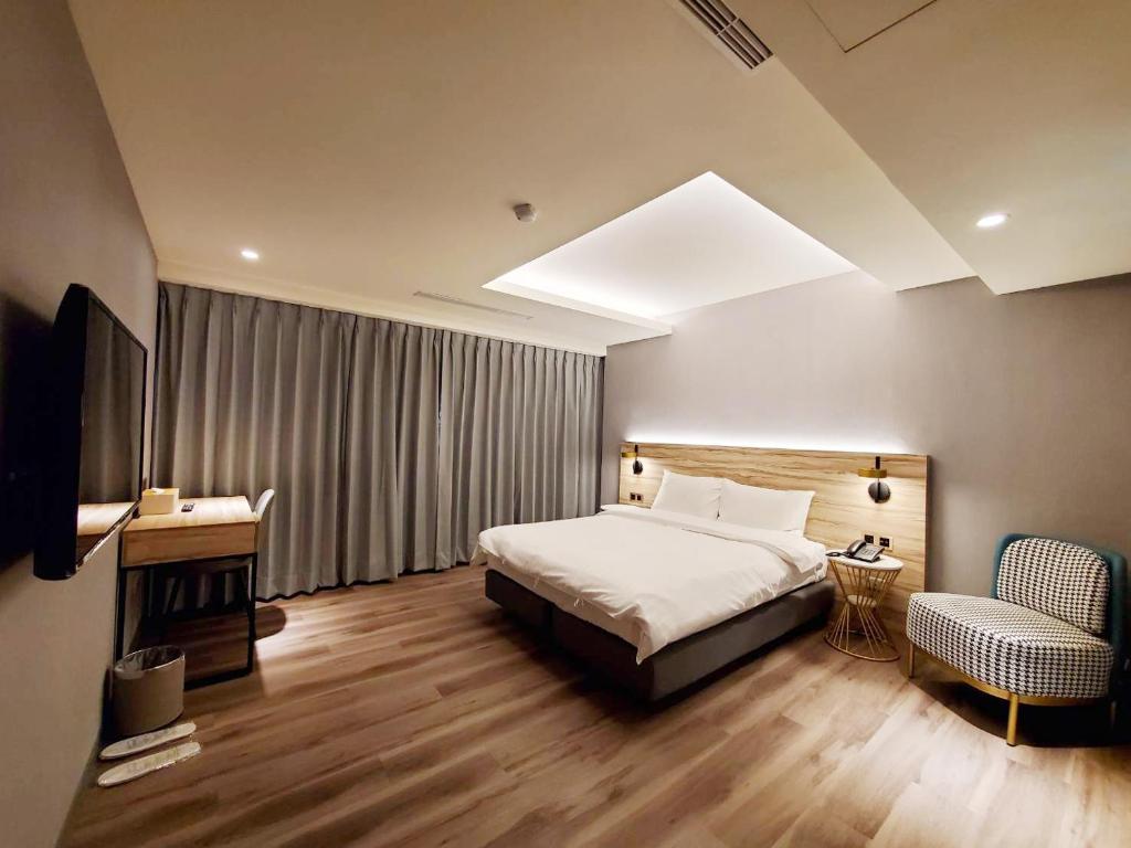 a bedroom with a bed and a tv and a chair at HINOEN Hotel in Taipei