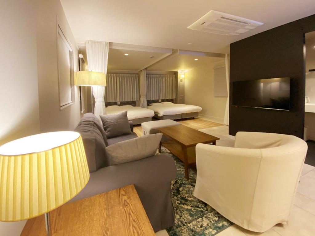 a living room with a couch and chairs and a tv at precious days inn in Fukuoka