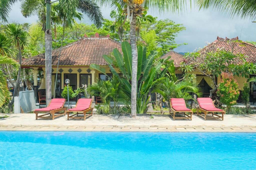 a group of chairs and a pool in front of a house at RedDoorz at Tanjung Alam Hotel Lovina in Buleleng