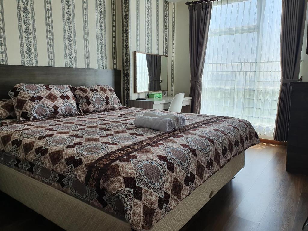een slaapkamer met een bed met een quilt bij Comfy Apartment Grand Sungkon Lagoon in Dukuhpakis